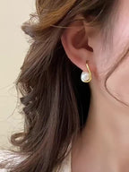 Unbranded close-worn photo of a gold-tone curved teardrop frame around a white round bead.