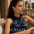 Seated model in navy halter top wearing the gold-tone teardrop frame and round white bead.