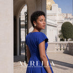 Model in a bright blue dress looking back in a courtyard, wearing the oval white-and-gold-tone whirl stud.
