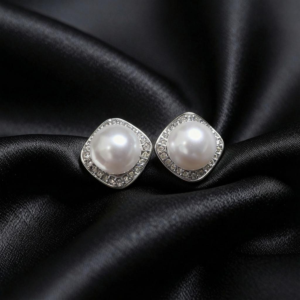 Pair of silver-tone cushion-square halo studs with round white centers on black satin.