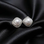 Pair of silver-tone cushion-square halo studs with round white centers on black satin.