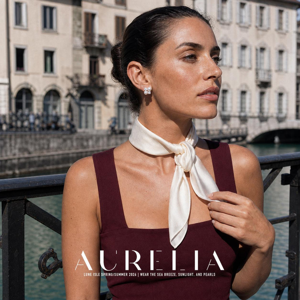 Waist-up portrait in a burgundy dress and pale scarf beside a canal, with the cluster earring visible.