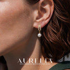 Close ear view showing the paired stone-set bars, short connecting ring and round white drop.