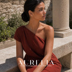Seated side portrait in rust one-shoulder dress with the horizontal two-flower cluster visible.