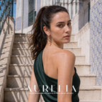 Model in a green one-shoulder outfit on stone steps, wearing the long curved gold-tone drop with white bead ends.