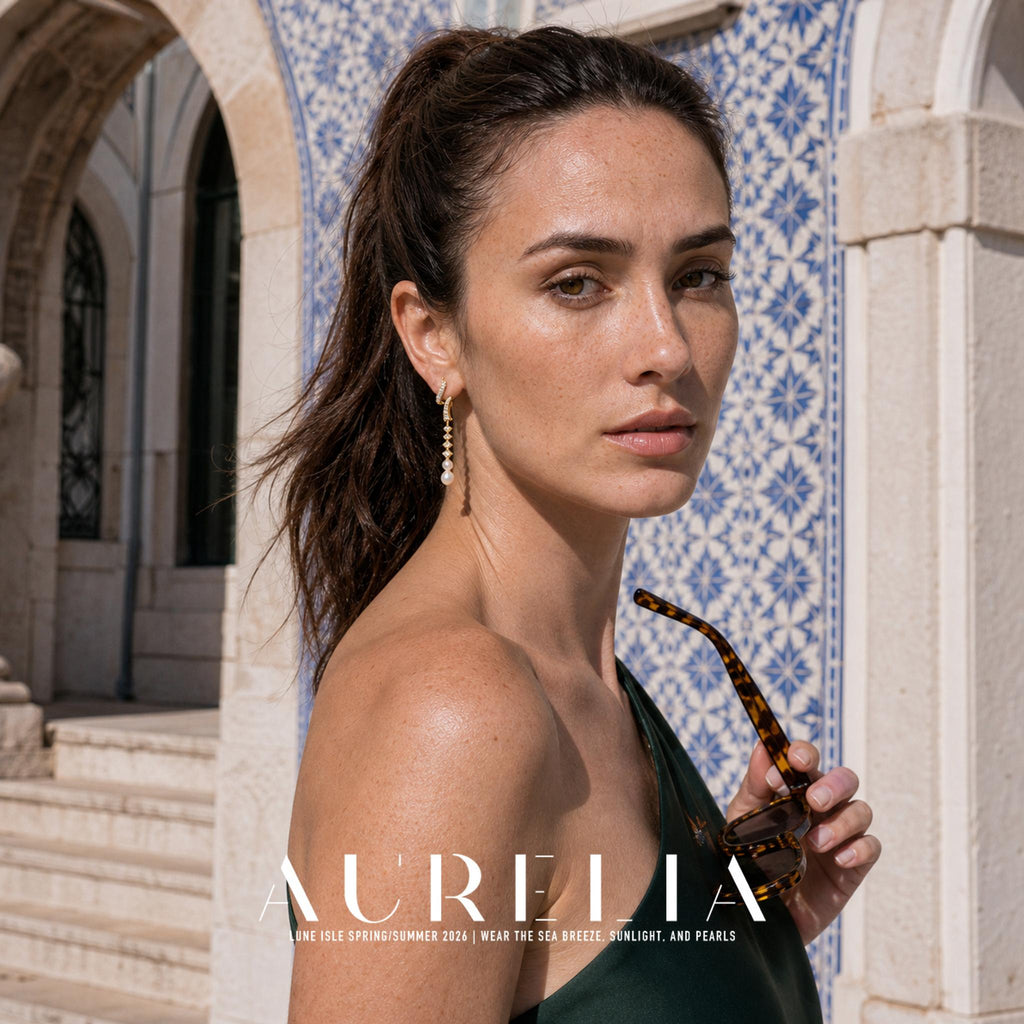 Over-shoulder portrait with sunglasses showing long curved gold-tone drop earrings.