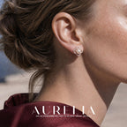 Close view of a four-lobed floral openwork stud with a round white center, clear accents and a warm rose-gold-tone frame.
