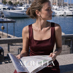 Model in a burgundy outfit holding a map by a marina, wearing the floral white-center stud.