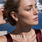 Close portrait with hand in hair showing warm-tone four-lobed floral stud.