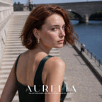 Over-shoulder riverside portrait wearing beaded gold-tone hoop.