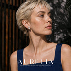 Head-and-shoulders model portrait in a blue dress, with the triangular bead cluster visible on the ear.