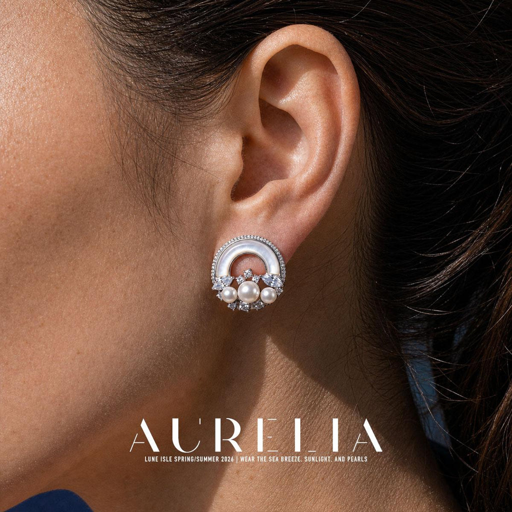 Close view of the circular earring: a pale upper arch around an opening and three round white beads across its lower section.