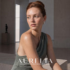 Seated model in a green one-shoulder dress in an interior, with the butterfly-and-bead earring visible.
