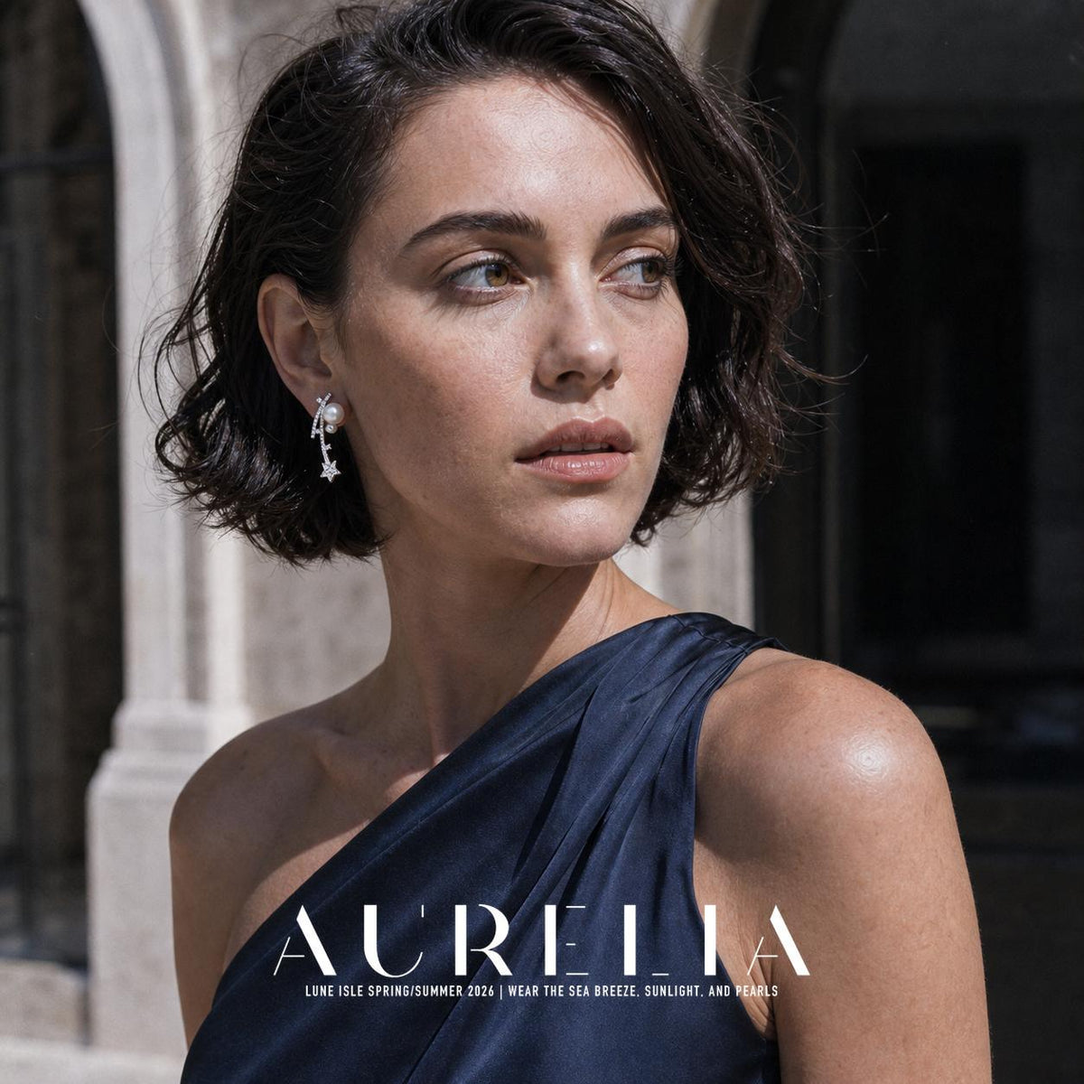 Shoulder-up portrait in a dark one-shoulder dress; earring shows unequal white beads, curved stone trails and the terminal star.