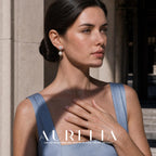 Model in a pale blue dress at a stone doorway, showing the same flower-and-drop earring.