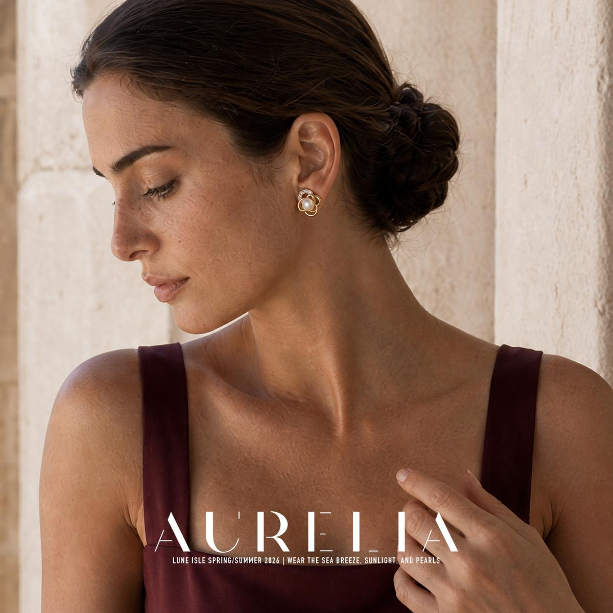 Model in a burgundy dress beside pale stonework, wearing the same open-loop flower stud.