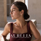 Seated side portrait in burgundy with open layered gold-colored flower loops around white center bead.