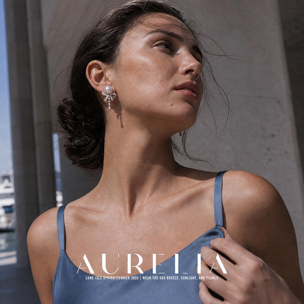 Low-angle model portrait wearing round white top above open bow and slender dangling accent row.