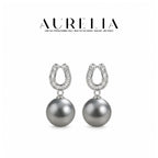 Front-facing pair of silver-colored earrings on white, with open horseshoe-shaped tops containing narrow clear rectangular details and dark gray round drops.