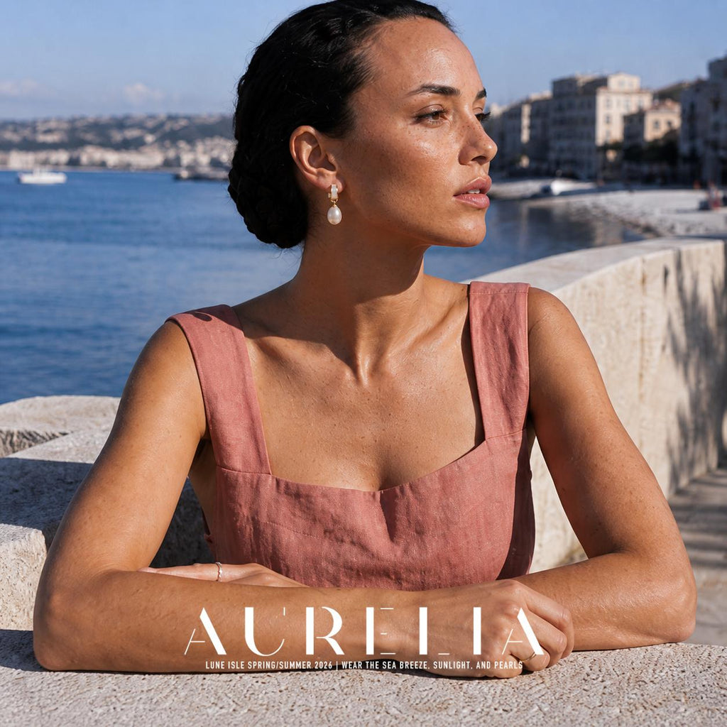 Seated waterfront portrait showing the pale inset short hoop with gold-colored edges and hanging white oval drop.