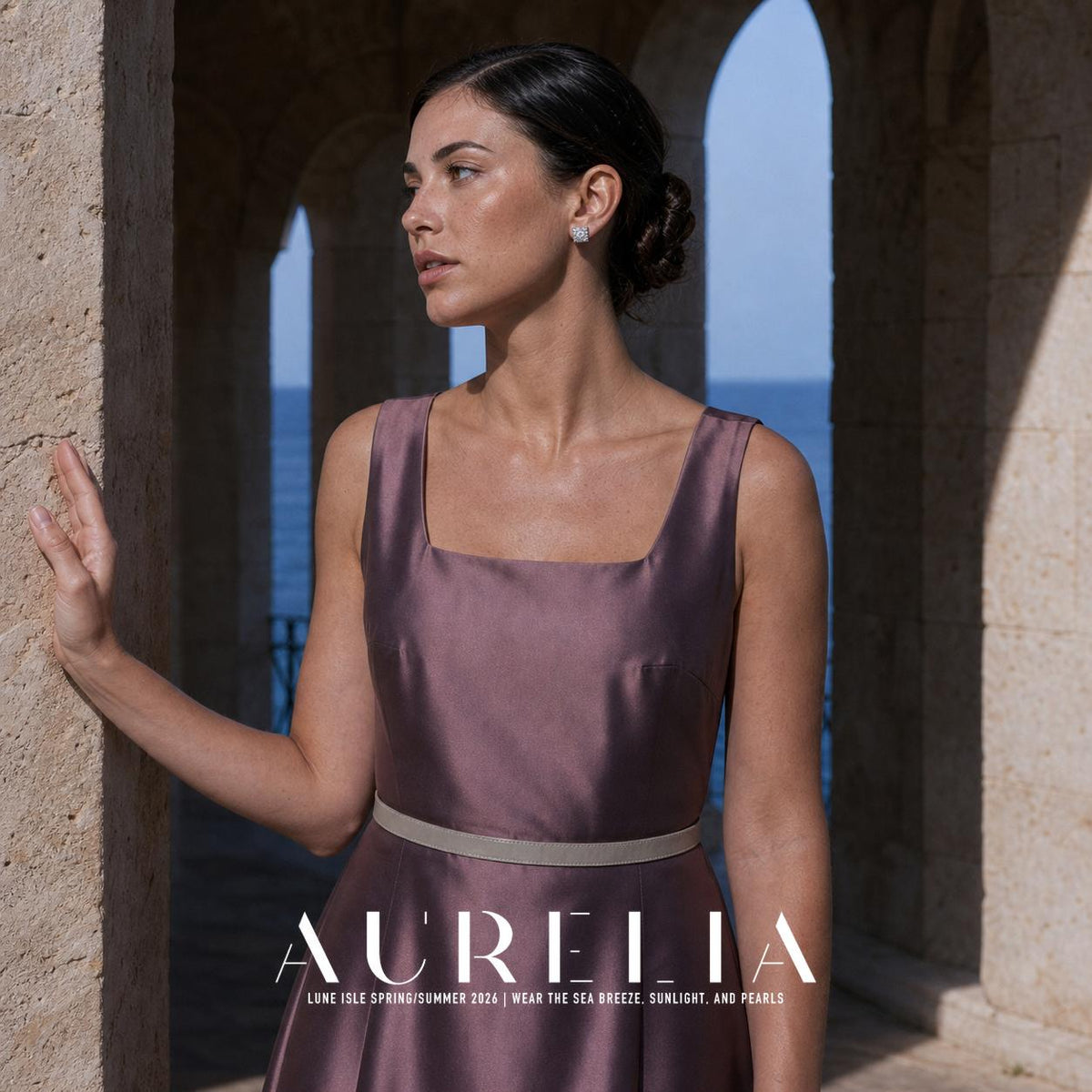 Person in a gray-purple sleeveless dress with a pale belt, standing among stone arches and wearing a small silver-colored square stud with clear accents.