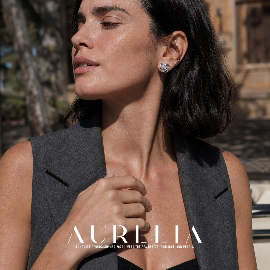 Chest-up portrait with hand at lapel, showing the interlaced silver-tone loop bands and central stone.