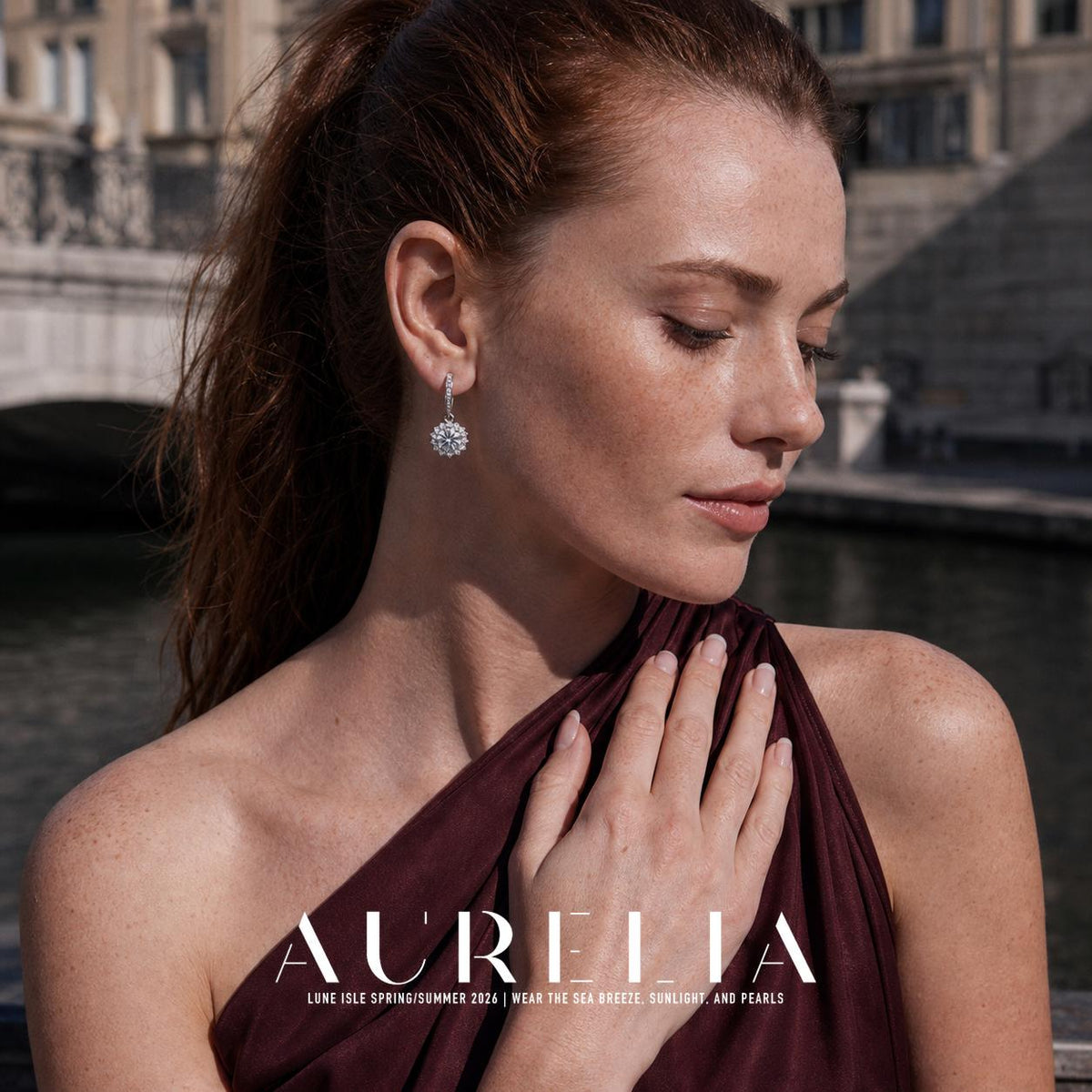 Canal-side portrait in a burgundy one-shoulder dress with the sunflower drop clearly visible.