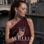 Canal-side portrait holding a glass shows the slim clear-set hoop, connector and sunflower-shaped drop.