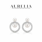Clean studio pair in silver tone: small upper white bead and larger bead suspended inside a clear-stone circular frame.