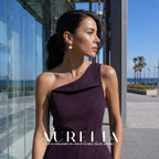 Wider standing portrait in a purple one-shoulder dress beside glass architecture, showing the same bead-and-fan silhouette.