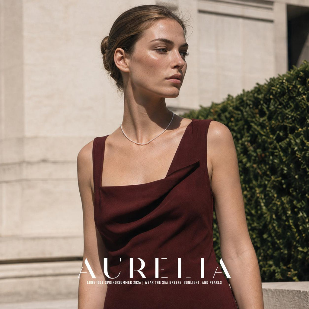 Upper-body portrait in a burgundy dress outdoors, with the single bead strand visible around the neck.