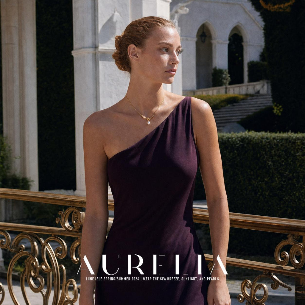 Wider outdoor portrait in a one-shoulder plum dress showing the necklace worn at the collarbone.
