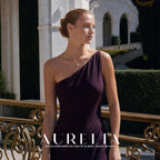Wider outdoor portrait in a one-shoulder plum dress showing the necklace worn at the collarbone.