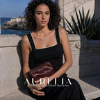 Seated model with clutch showing the curved bead cluster necklace at the neckline.