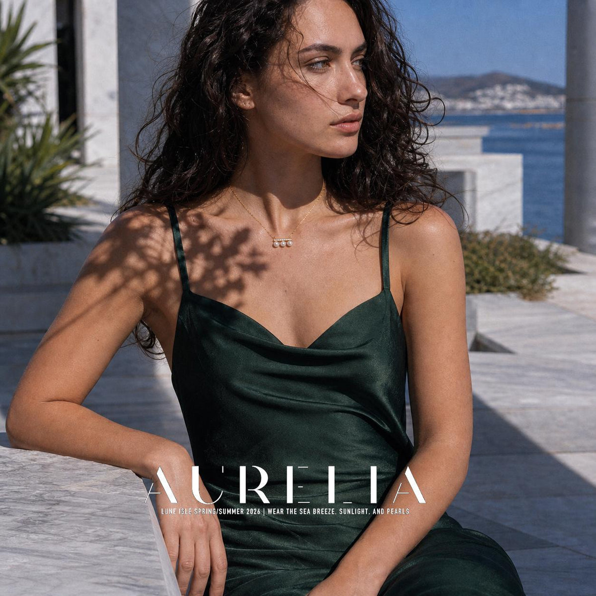 Seated side-looking waterfront portrait, necklace centered above green neckline.