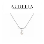 Clean silver-tone necklace still with shallow clear-stone wave and single white teardrop bead.