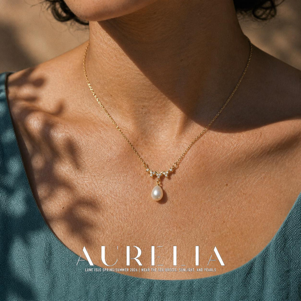 Close chest view of the fine chain, downward-pointed decorative wave and teardrop-shaped white bead.