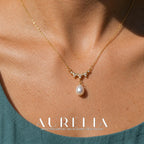 Close neckline view showing the stone-set wave and single white drop.
