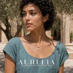 Upper-body courtyard portrait with the necklace centered above a teal neckline.