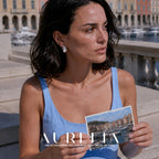 Seated marina portrait holding a postcard, with swirl earring unobstructed.