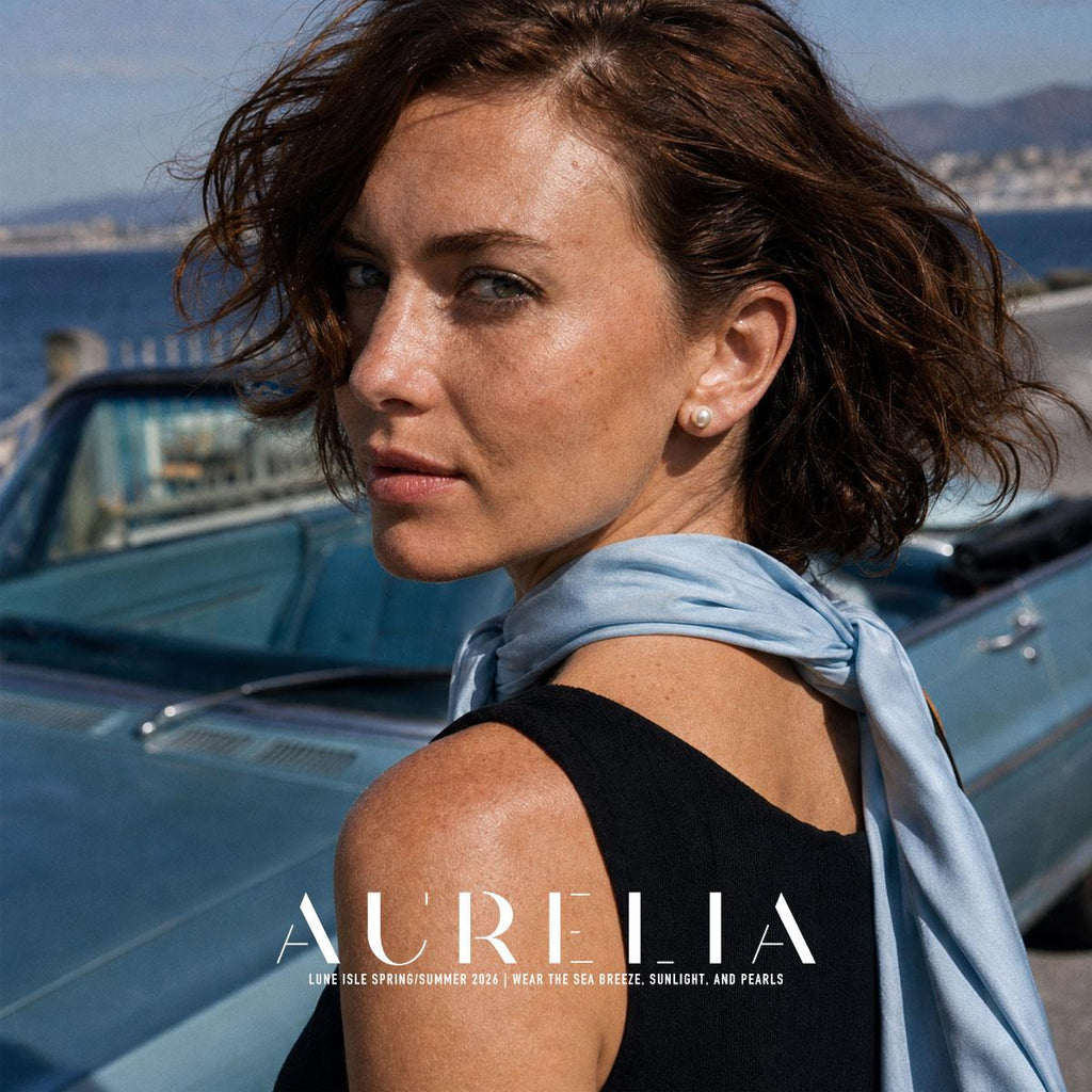Model in a black top and blue scarf in front of a car, wearing the simple white stud.