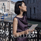 Model in a dark purple dress holding a map on a canal bridge, with the same stud-and-white-drop structure visible.