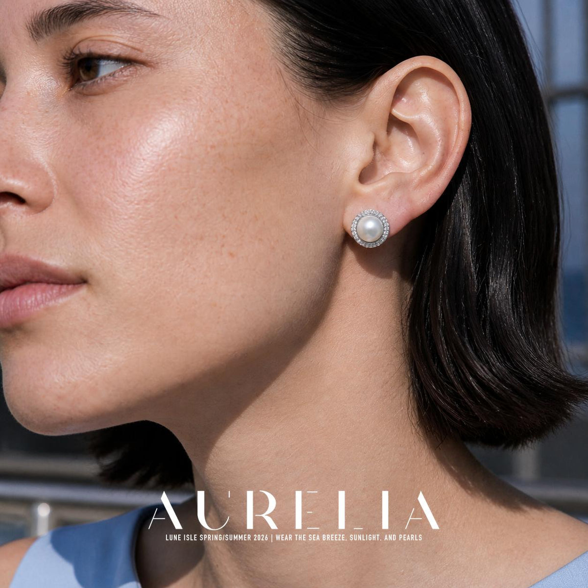 Close view of a silver-tone circular stud with a round white pearl-like center and clear-accent halo.