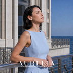 Model in a pale blue dress by a railing, wearing the small round white-center halo studs.