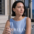 Model holding a glass, wearing circular silver-tone halo stud with white center.