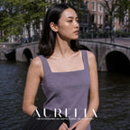 Waist-up canal-side portrait in lavender with simple round white stud visible.