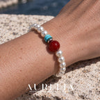 Close wrist view from the opposite angle. White bead strand with one larger red round accent, two turquoise-colored disc spacers and a silver-colored spacer; all worn views preserve this arrangement.