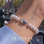 Close wrist view showing the oval clasp. Single row of white round beads with a smooth oval silver-colored clasp; the close clasp view matches the main, and other worn views show the same plain strand. No worn photo is assigned to an exclusive size variant.