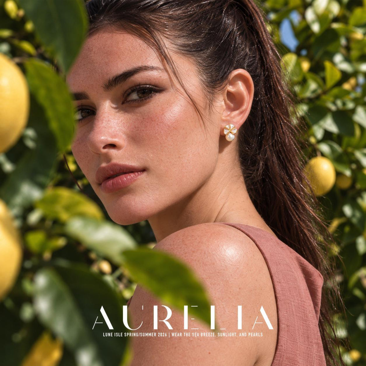 Over-shoulder portrait among leaves with matching folded flower and white round bead below.