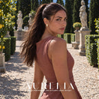 Model in a muted rose dress looking over her shoulder in a garden, wearing the same folded-flower stud.